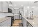 This modern kitchen includes gray cabinets, granite countertops, stainless steel appliances, and access to the pantry at 12706 Heath Grove Dr, Huntersville, NC 28078