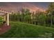 Green backyard with a lush lawn, trees, and sunset sky at 12912 Bailey Rd, Cornelius, NC 28031