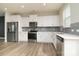 Contemporary kitchen features white cabinets, stainless steel appliances, and wood flooring at 13304 Porter Creek Rd, Charlotte, NC 28262
