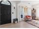 Inviting entryway featuring a modern black door, light wood floors, and a cozy pink chair at 14024 Alley Son St, Huntersville, NC 28078