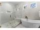 Bright bathroom features a soaking tub and glass enclosed shower with marble tile and bronze fixtures at 209 Sardis Ln, Charlotte, NC 28270