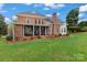 Expansive backyard featuring a brick house with a covered porch, lush lawn, and manicured landscaping at 21721 Shoveller Ct, Cornelius, NC 28031