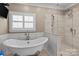 Bright bathroom with a soaking tub, a glass shower, and modern tile work at 21721 Shoveller Ct, Cornelius, NC 28031