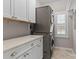 Bright laundry room with gray washer/dryer, white cabinets, and stone countertops at 21721 Shoveller Ct, Cornelius, NC 28031