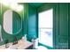 Stylish powder room featuring bold green walls, modern fixtures, and a sleek oval mirror at 3105 Beans Blvd, Charlotte, NC 28203