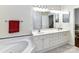 Bright bathroom featuring double sink vanity, large mirror, and a soaking tub with tile surround at 3721 Oak View Ct, Matthews, NC 28105