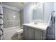 Light and airy bathroom with gray vanity, a tub with tiled shower, and modern fixtures at 4487 Catawba Burris Rd, Denver, NC 28037