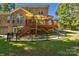 View of a backyard with a raised deck, brick home, and black metal fencing at 4586 Chanel Ct, Concord, NC 28025