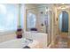 Bright bathroom features a tiled soaking tub, a glass enclosed shower, and a large window with blinds at 4586 Chanel Ct, Concord, NC 28025