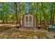 Charming backyard shed with double doors, surrounded by lush trees and flowering plants at 4586 Chanel Ct, Concord, NC 28025
