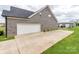 View of the attached two-car garage with a wide driveway and a detached garage in the background at 514 Baucom Deese Rd, Monroe, NC 28110