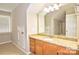 Bright bathroom featuring granite countertops and cabinets, with a large mirror, and a window for natural light at 5344 Saddlewood Ln, Mint Hill, NC 28227