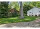 Spacious backyard featuring a well-maintained lawn, mature trees, and a charming brick and white-sided detached garage at 5400 Glenham Dr, Charlotte, NC 28210