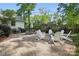 Large patio area with Adirondack chairs, a fire pit, and mature landscaping at 5400 Glenham Dr, Charlotte, NC 28210