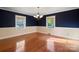 Open dining room with hardwood flooring, two windows, a blue accent wall, and elegant chandelier lighting at 631 Dogwood Rd, Statesville, NC 28677