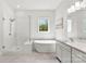 This bathroom features a glass-enclosed shower, a freestanding tub, and a large window with a view of the trees at 7500 Happy Hollow Dr, Mint Hill, NC 28227