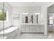 Bright bathroom featuring double sinks, large mirrors, a soaking tub, and tile flooring with views to the exterior at 7500 Happy Hollow Dr, Mint Hill, NC 28227
