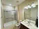 Well-lit bathroom features a bathtub with glass doors, a toilet, and a sink with cabinets at 7581 Short Putt Ct, Charlotte, NC 28215