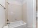 Bathroom with white tile, a shower head, and tub with white tile surround at 7854 Springs Village Ln, Charlotte, NC 28226