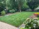 Well-maintained backyard with lush green grass, flower beds, and a black metal fence at 9727 Glenburn Ln, Charlotte, NC 28278