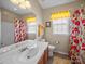 Bathroom features a single sink vanity, toilet, and shower/tub with vibrant floral curtains at 9727 Glenburn Ln, Charlotte, NC 28278