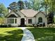 Charming white brick home features manicured lawn, a welcoming walkway and lush landscaping at 105 Beach Ln, Mooresville, NC 28117