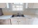 Kitchen sink with white cabinets and modern fixtures under a window with natural light at 11630 Retriever Way, Charlotte, NC 28269