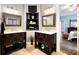 Dual vanity bathroom with dark wood cabinets, decorative mirrors, and built-in shelving, leading to the bedroom at 1214 Foxfield Rd, Waxhaw, NC 28173