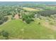 An aerial shot of a grassy field and trees, with a few houses in the distance, surrounded by lush greenery at 201 Lee Black Rd, Cherryville, NC 28021