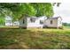 View of the backyard of a white home with a brick foundation and mature trees at 201 Lee Black Rd, Cherryville, NC 28021
