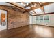 Open living room features a brick wall, beamed ceilings, and wood floors at 3987 Taxahaw Rd, Lancaster, SC 29720