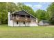View of the home with a light grey storage shed, black upper level, white brick foundation, and inviting wood balcony at 5316 Teakwood Dr, Kannapolis, NC 28083