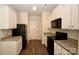 Functional kitchen showcasing granite countertops, white cabinets, and modern black appliances at 8606 Highgate Dr, Charlotte, NC 28215