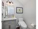 Modern half bath with white fixtures, gray vanity, framed artwork, and stylish mirror at 9422 Ridgeforest Dr, Charlotte, NC 28277