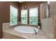 A bathroom with a large tub, bright windows, and tile flooring at 10125 Loch Lomond Dr, Charlotte, NC 28278
