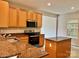 A well-lit kitchen featuring granite countertops, wood cabinets, stainless appliances, and a kitchen island at 12815 Towering Pine Dr, Charlotte, NC 28269