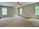 Spacious carpeted primary bedroom illuminated by natural light through multiple windows and ceiling fan at 12815 Towering Pine Dr, Charlotte, NC 28269