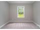 Bedroom features neutral carpet, base trim and a window with a treed view at 1721 Balfour Ln, Charlotte, NC 28216