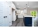 Modern kitchen features white cabinets, gray floors, and a blue kitchen island with quartz countertops at 1721 Balfour Ln, Charlotte, NC 28216