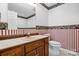 Bathroom featuring wood vanity with sink, toilet, mirror, and decorative wallpaper at 3730 Club House Ne Dr, Conover, NC 28613