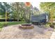 Backyard featuring a stone fire pit with chairs, trees, a utility shed, and gravel at 412 W D Ave, Salisbury, NC 28144