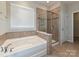 Well-lit bathroom features a soaking tub, glass-enclosed shower, and neutral tile accents at 4425 Marlay Park, Indian Trail, NC 28079