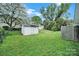 View of the backyard featuring a storage shed and well-maintained lawn with mature trees and partial fence at 5876 Wedgewood Dr, Charlotte, NC 28210
