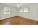 This bright bedroom features hardwood floors, base molding, white walls, two windows and a ceiling fan at 5876 Wedgewood Dr, Charlotte, NC 28210
