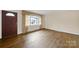 Inviting living room featuring hardwood floors, a large window with charming curtains, and a welcoming front door at 5876 Wedgewood Dr, Charlotte, NC 28210