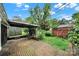 Brick patio and backyard featuring an outdoor structure, seating area, lush foliage, and mature trees at 5876 Wedgewood Dr, Charlotte, NC 28210