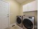 Well-equipped laundry room with stainless steel washer and dryer, white cabinets, and tile floor at 6144 Abergele Ln, Matthews, NC 28104
