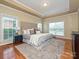 Spacious primary bedroom featuring a tray ceiling, plush carpet, and natural light from the windows at 6144 Abergele Ln, Matthews, NC 28104