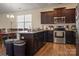 Eat-in kitchen featuring dark wood cabinetry, stainless steel appliances, and a granite-topped island at 6816 Pennyroyal Way, Charlotte, NC 28216