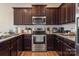 Well-equipped kitchen with stainless steel appliances, dark cabinets, granite countertops, and hardwood floors at 6816 Pennyroyal Way, Charlotte, NC 28216